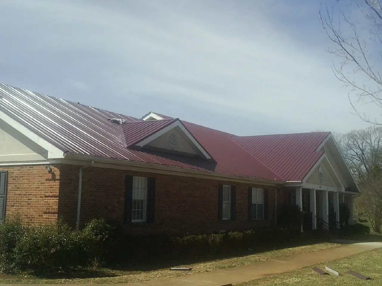 Red metal roof with gabled entries on a long brick building in Jud