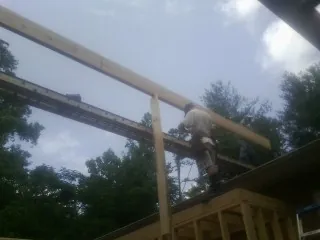 Carpenter setting a ridge beam over a new addition frame — Ice Dam Removal by Roofing Brothers in Jud