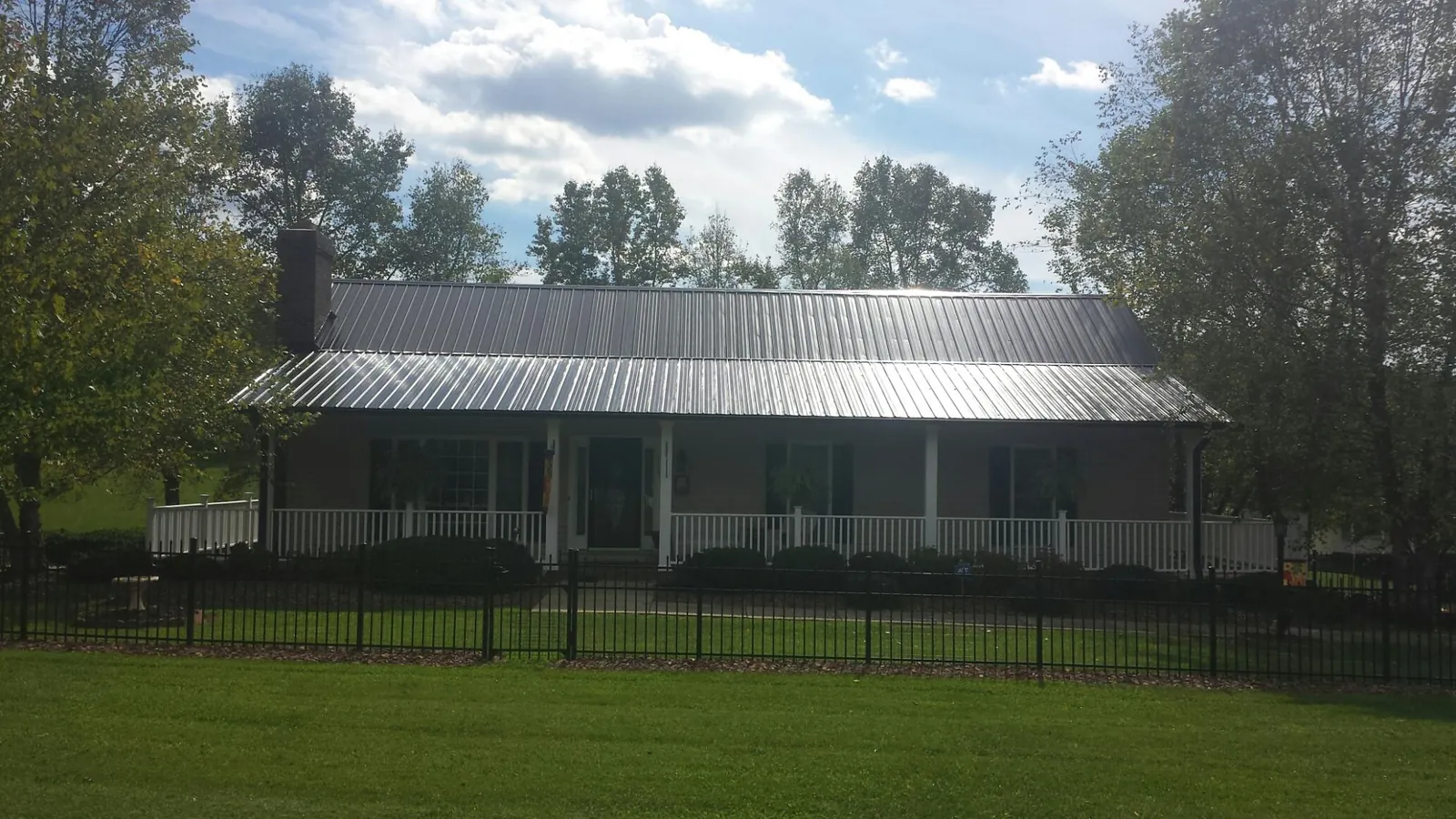 Gray metal roof on a brick ranch with a full width front porch — Gutter Guard Installation work by our crew in Jud