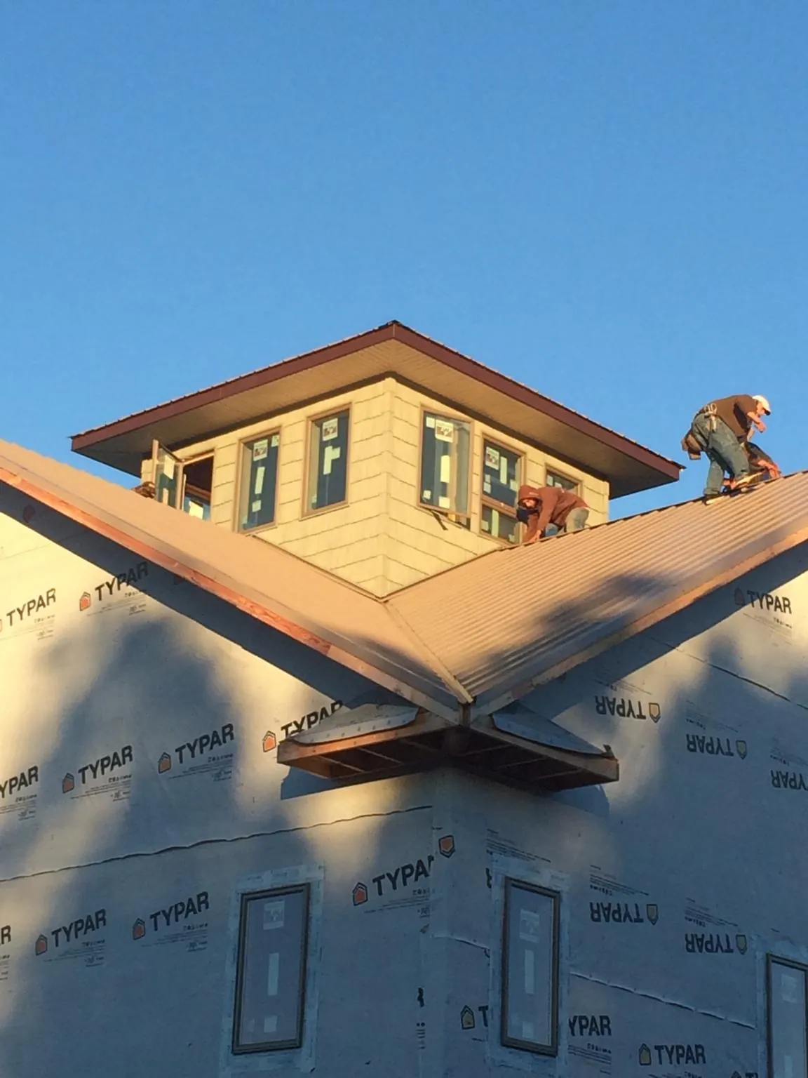 Roofers working around a rooftop cupola on a new metal roof at sunset — Roof Waterproofing in Jud by Roofing Brothers
